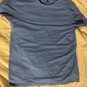 Blå t-shirt från Tommy Hilfiger - Snygg blå t-shirt från Tommy Hilfiger med en liten logga på bröstet. Perfekt för en avslappnad stil. Tillverkad i mjukt material för extra komfort.