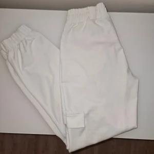 Vita cargobyxor med fickor - Säljer ett par vita cargobyxor med elastisk midja och praktiska fickor på sidorna. Perfekta för en avslappnad stil. Lite nopprig på ett ställe, se sista bilden. Garderobsrensning så kika gärna på övriga auktioner. 