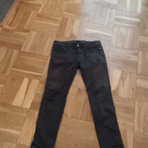 Svarta jeansbyxor - Snygga svarta jeansbyxor med en klassisk design. De har en rak passform och är utrustade med både knappar och dragkedja. Perfekta för en stilren look. Replay. 34,32