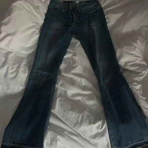 Lågmidjade blå bootcut jeans - Snygga blå bootcut jeans med en klassisk design. De har en dragkedja och knappar framtill. Perfekta för en avslappnad stil.
