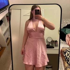 Rosa halterneck klänning - Säljer denna satin klänning då den tyvärr inte kommer till användning, det är några små blåa fläckar på högra sidan (se bild). Har inte provat ta bort de, klänningen är använd fåtal gånger. klänningen är slutsåld hos Zara och nypris 379 kr. 