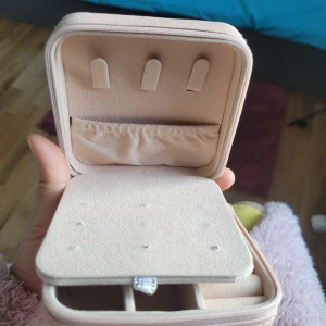 Rosa smyckeskrin med dragkedja - Praktiskt och stilrent rosa smyckeskrin med dragkedja. Insidan har flera fack och hållare för att organisera smycken som ringar, örhängen och halsband. Perfekt för resor eller förvaring hemma.