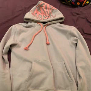 Syna wrld  - Säljer en perfekt syna wrld hoodie. Perfekt för en avslappnad stil. Den har en praktisk magficka och långa ärmar. Bra skick, dm vid intresse