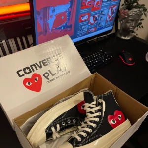 Converse Play Comme des Garçons sneakers - Snygga svarta Converse Play Comme des Garçons sneakers med det ikoniska röda hjärtat på sidan. Skorna har klassisk snörning och vit sula. Perfekta för en stilren look med en twist.