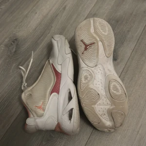 Jordans - Snygga vita och rosa sneakers från Jordan med snörning och en stilren design. Skorna har en mjuk rosa insida och en vit yttersula med rosa detaljer. Perfekta för en sportig look.