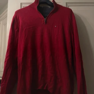 Röd half zip från Tommy Hilfiger - Säljer en snygg röd tröja från Tommy Hilfiger med dragkedja vid halsen. Tröjan har långa ärmar och en liten logotyp på bröstet. Perfekt för kyligare dagar. Quarter zip