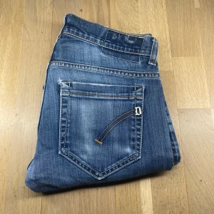 Blå jeans från Dondup - Snygga blå jeans från Dondup med en klassisk femficksdesign och slitna detaljer. De har en dragkedja och knapp framtill samt kontrastsömmar som ger en cool look. Perfekta för en avslappnad stil.
