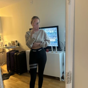 Svarta leggings från Stronger - Snygga svarta leggings från Stronger med elastisk midja och ett coolt randigt mönster på ena benet. Perfekta för träning eller en avslappnad dag. De är stretchiga och bekväma, vilket gör dem till ett måste i garderoben.