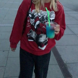 Röd sweatshirt med grafiskt tryck - Säljer en cool röd sweatshirt med ett stort grafiskt tryck på framsidan. Tröjan har en avslappnad passform och långa ärmar, perfekt för en casual look. Passar bra till jeans eller leggings.