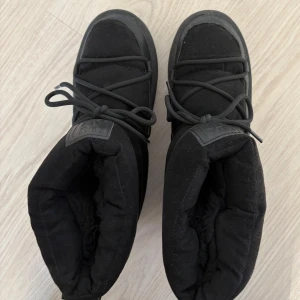 Svarta vinterboots med snörning - Säljer ett par svarta vinterboots i mycket bra skick. De är varma och perfekta för kalla dagar. Skorna har en snygg snörning framtill och är gjorda i ett slitstarkt material. Perfekta för vinterns alla äventyr! Från hm och påminner om inuikii