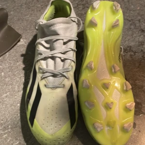 Adidas crazyfast fotbollsskor - Säljer ett par coola fotbollsskor med limegrön sula och svart-vita detaljer. Skorna kan användas på både gräs och konstgräs. Av andvändning har  skorna fått lite svarta kanter men har försökt att få bort det mesta. Skorna har snörning och är perfekta för fotbollsträning. De är i bra skick och redo för nya äventyr på planen!