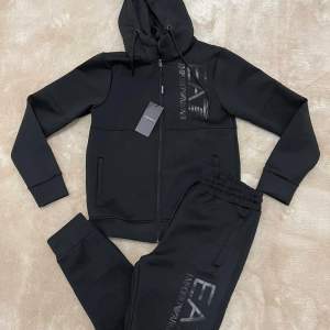 Säljer en stilren svart hoodie från Emporio Armani. Den har dragkedja och en justerbar huva. Perfekt för en casual look eller träning. Märkesloggan syns tydligt på bröstet. Passar både höst och vår.