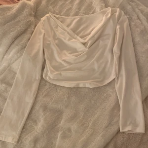 Tröja  - Vit urringad tröja med ett fint lyft där fram. Använd några gånger, men används inte längre därför säljer jag. Storlek M, den är även slutsåld.  