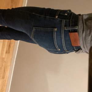 Säljer ett par snygga mörkblå jeans från Acne i bra skick. De har en klassisk femficksdesign och är tillverkade i slitstarkt denim. Perfekta för både vardag och fest! Passformen är slim och de har en hög midja för en bekväm och stilren look.