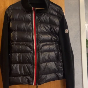 Svart pufferjacka från Moncler - Säljer en snygg svart Cardigan från Moncler. Jackan  Perfekt för höst och vinter med sina långa ärmar och quiltade design. Den är i mycket bra skick och passar perfekt för både vardag och fest.Hör av er om ni vill ha mer bilder eller andra funderingar🍾