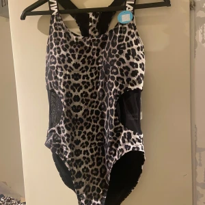 Leopardmönstrad baddräkt - Säljer en supercool leopardmönstrad baddräkt i nytt skick. Den har en snygg och modern design med svarta detaljer på sidorna. Perfekt för både bad och träning! 🐆