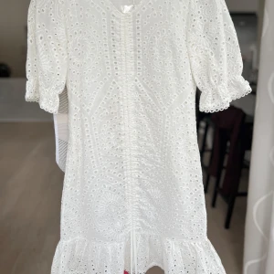Vit klänning med spetsdetaljer - Säljer en superfin vit klänning  med v-ringning och spetsdetaljer. Den har korta ärmar och en volangkant längst ner. Perfekt för sommarens alla fester! 💫