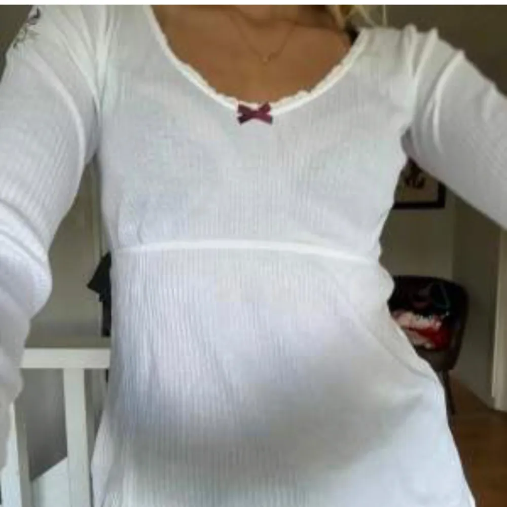 Säljer en superfin vit långärmad topp med en söt liten rosett framtill. Toppen har en v-ringad design med spetskant som ger en romantisk touch. Perfekt för både vardag och fest! Passar bra till jeans eller kjol. 💫. Neuletakit & Villapaidat.