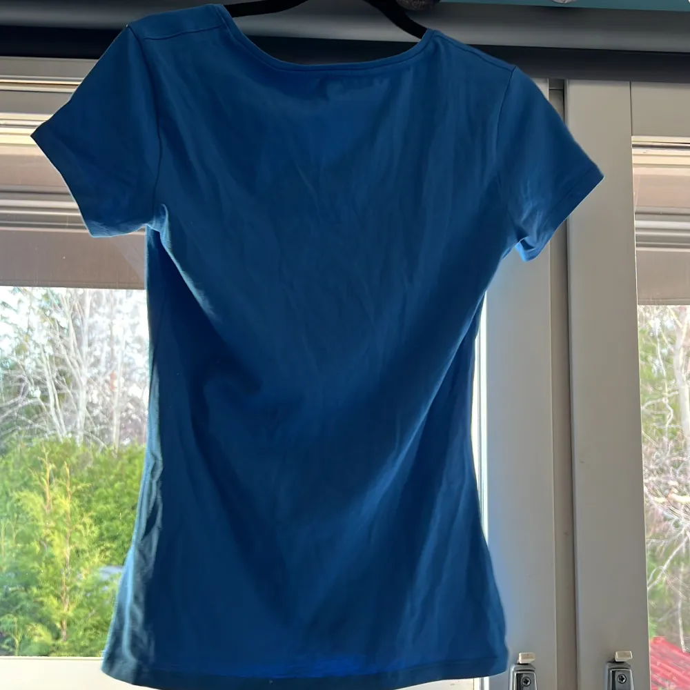 Säljer en snygg blå t-shirt i bomull från Cubus. Den har en v-ringad hals och korta ärmar, perfekt som både undertröja och vanlig T-shirt. Den är i mycket bra skick och passar till både vardag och fest. Skön och stilren design!. T-shirts.