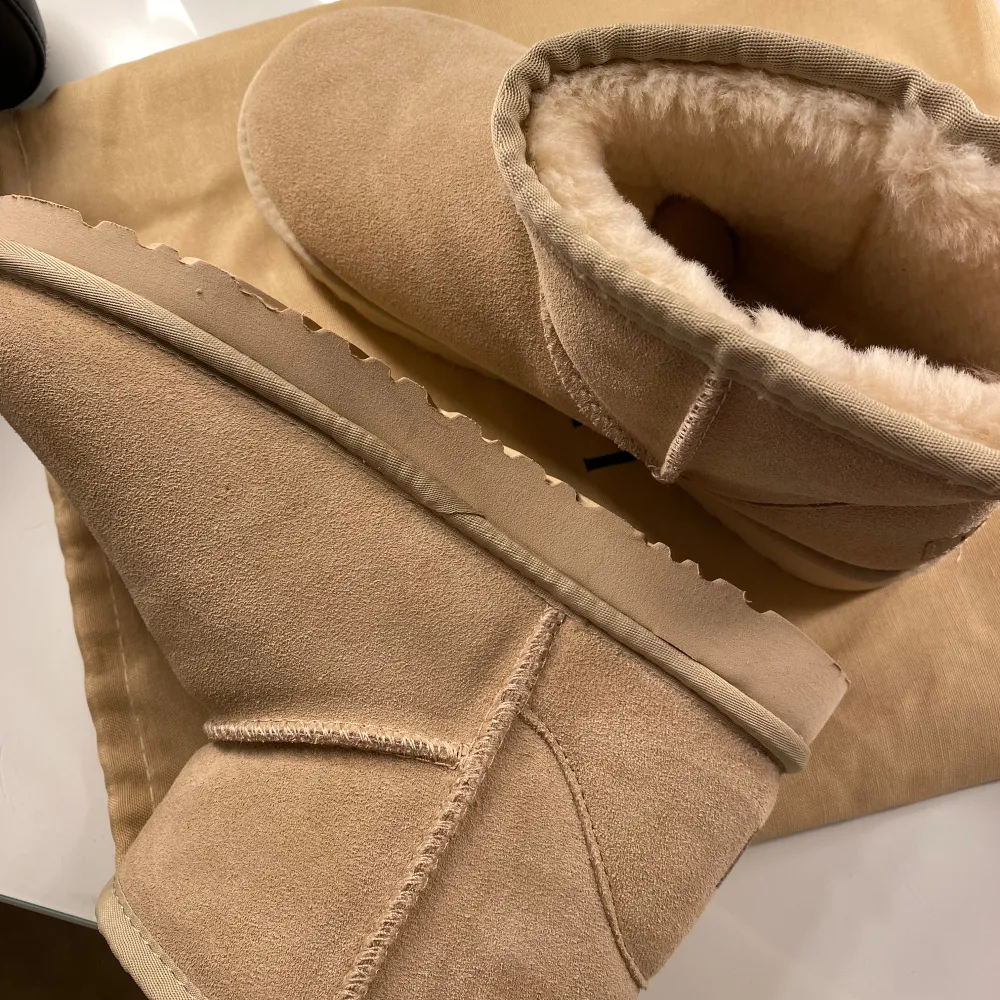 Säljer ett par supermysiga ljus beiga boots från UGG i nytt skick. De är gjorda av mocka och har en fluffig insida som håller fötterna varma under kalla dagar. Perfekta för höst och vinter! 🧡 nytt skick aldrig använda! Äkta.. Kengät.