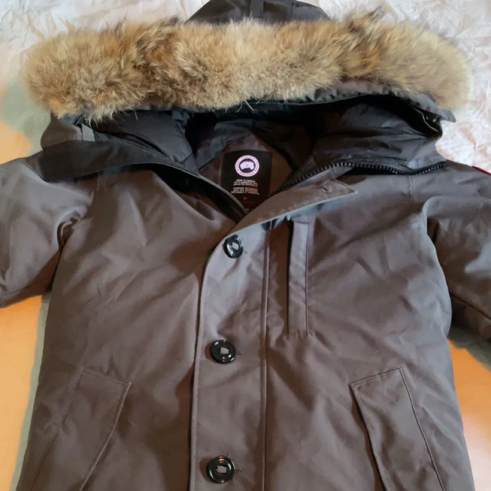 Säljer en grå parkajacka från Canada Goose i mycket bra skick. Jackan har en pälskantad huva och stängs med både dragkedja och knappar. Perfekt för kalla vinterdagar! 🧥❄️jackan är i storlek S och för fler bilder elelr Info är det bara att fråga. Priset går att diskutera vid en snabb o smidig affär🧊🧊. Jackor.