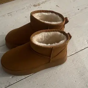 Säljer ett par bruna boots i syntetmaterial med mjukt foder inuti. Perfekta för kalla dagar med sin varma insida. De har en enkel design utan snörning och en robust sula för bra grepp. Märket 'Sport Best Fashion' syns på baksidan. Perfekta för vintern! ❄️