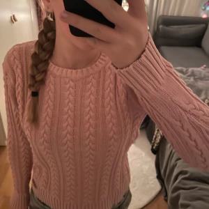 Rosa stickad tröja - Säljer en superfin rosa stickad tröja med flätmönster. Den är perfekt för kyliga dagar och har en skön passform. Tröjan är långärmad och har ribbade muddar vid ärmslut och nederkant. Storlek S, passar mig som är 168 för referens❤️