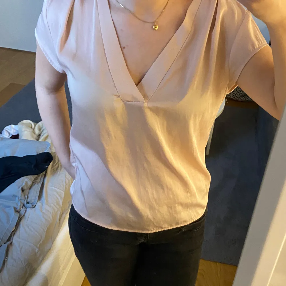 Säljer en stilren rosa blus från H&M Conscious. Den har en v-ringad design och korta ärmar, perfekt för både vardag och fest. Materialet känns mjukt och luftigt, vilket gör den skön att bära under varmare dagar.. Toppar.