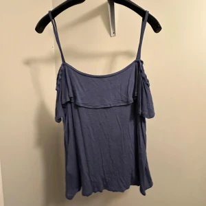 Blå offshoulder topp - Snygg blå offshoulder topp med smala axelband från Åhléns i storlek M. Materialet är mjukt och bekvämt och oanvänd!