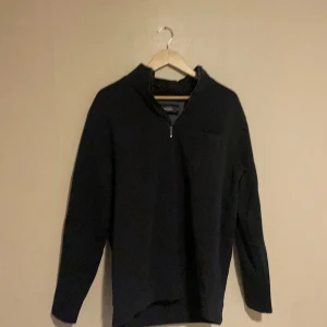 Mörkblå långärmad tröja med dragkedja - Säljer en mörkblå långärmad tröja i mycket bra skick. Den har en praktisk dragkedja vid halsen och är perfekt för både höst och vinter. Tröjan är bekväm och stilren, idealisk för vardagsbruk eller en avslappnad dag ute. Fungerar även till fester och andra finare tillfällen. Inga skador eller fläckar på tröjan! Ordinarie pris - 400kr. Regular fit.