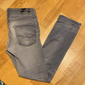 Grå jeans från Jack & Jones - Säljer ett par grå jeans från Jack & Jones, skick 8/10. Storlek 30/32. Jeansen har en slim passform och har en snygg tvättad look. Det är perfekta för både vardag och fest. Pris kan såklart diskuteras!