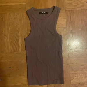 Brun ribbad linnetopp från Bik Bok - Säljer en snygg brun ribbad linnetopp från Bik Bok. XsToppen är ärmlös och har en tight passform som framhäver figuren. Superbekväm och lätt att matcha med andra plagg! Nästan aldrig varit använt.