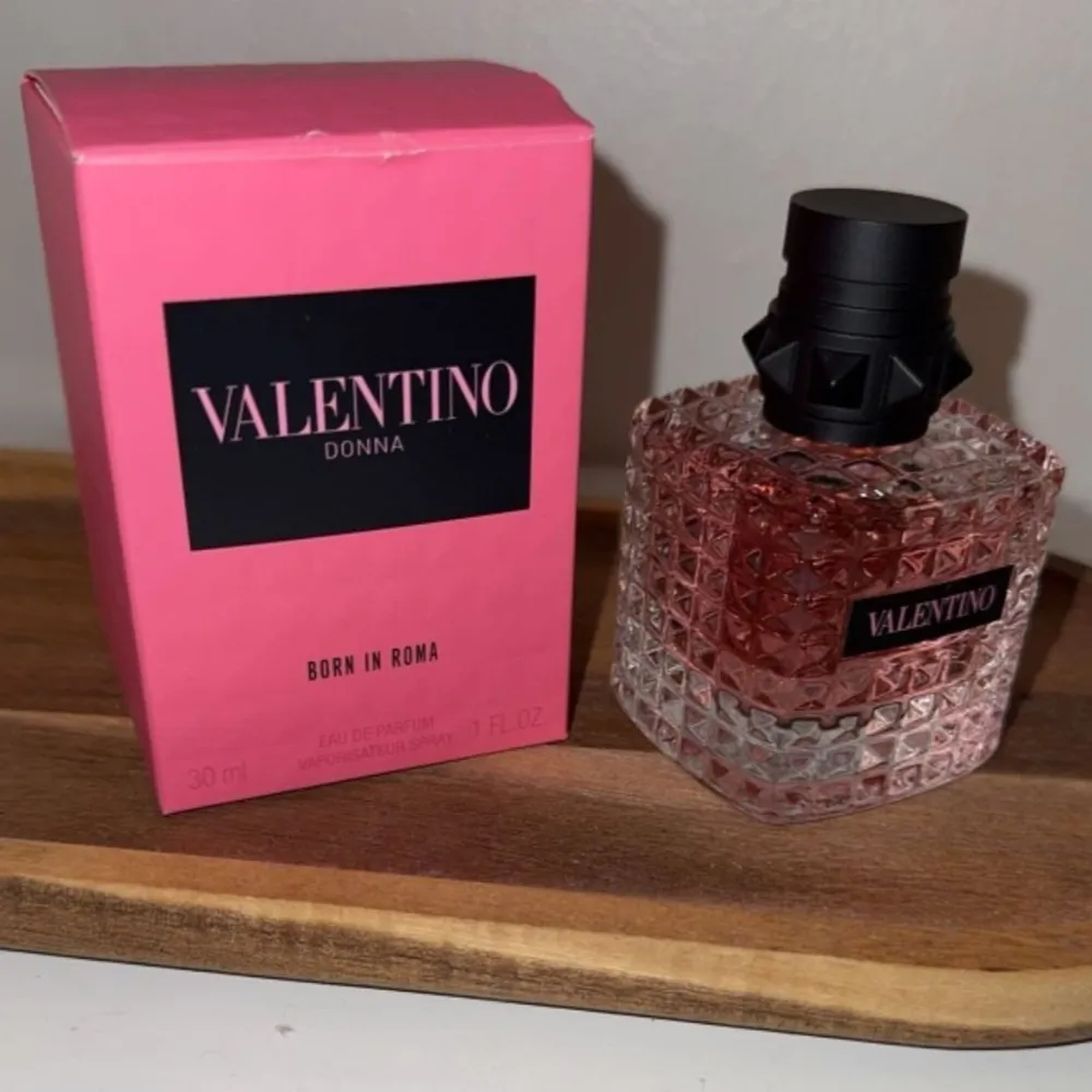 Säljer en lyxig Valentino Donna Born in Roma parfym. Flaskan är 30 ml och har en snygg, fyrkantig design med ett mönster av små pyramider. Den är rosa med en svart kork som har en cool, nitat look. Förpackningen är också rosa med svart text. Perfekt för att känna sig extra speciell! NY. Parfym.