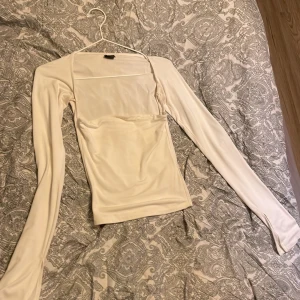 Vit långärmad topp från Gina Tricot - Säljer en stilren vit långärmad topp från Gina Tricot i storlek XS. Toppen har en enkel och elegant design, perfekt för både vardag och fest. Materialet känns mjukt och bekvämt mot huden.