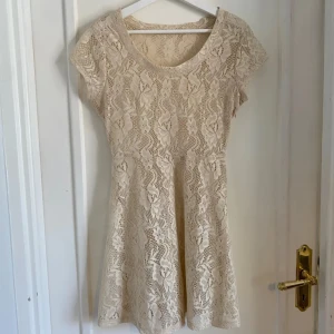 Beige spetsklänning - Söt beige klänning i spets så den är ganska genomskinlig. Klänningen har ett vackert blommönster och en dragkedja på sidan. Perfekt till sommaren. Hör av dig om du har frågor🫶
