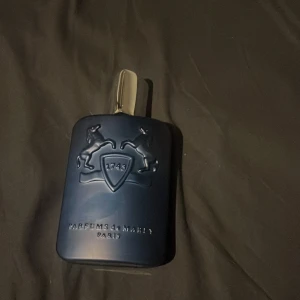 Parfym från Parfums de Marly (LAYTON) - Elegant parfym i en stilren mörkblå flaska med silverfärgad kork. Flaskan har en upphöjd design med två hästar och årtalet 1743. Perfekt för den som söker en lyxig doftupplevelse. Helt ny!