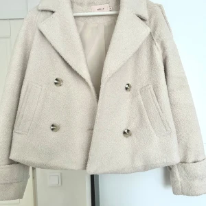 Beige teddyjacka från Nelly - Säljer en snygg beige/krämvit teddyjacka från Nelly med dubbelknäppning och stora knappar. Jackan har en croppad passform och långa ärmar. Perfekt nu till våren. Använd ett fåtal gånger och inga defekter💗💗