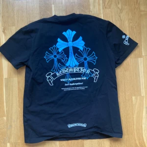 Chrome Hearts Blå T-shirt Medium - Snygg svart t-shirt från Chrome Hearts med ett stort blått tryck på ryggen och mindre tryck på bröstet och ärmen. Felstavat tryck därav priset se bilder.