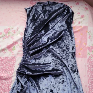Mörkblå sammet klänning - Elegant mörkblå klänning i mjuk sammet med en åtsittande passform. Klänningen har en vacker drapering på sidan som ger en stilfull look. Perfekt för speciella tillfällen.