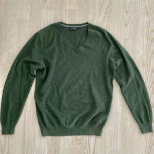 Grön kashmirtröja från Massimo Dutti - Säljer en stilren grön tröja från Massimo Dutti i en mjuk blandning av bomull och kashmir. Tröjan har en v-ringad hals och långa ärmar. Hittar ej storlek men sitter som S. 95% bomull, 5% Kashmir.