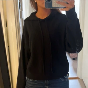 Svart stickad hoodie - Säljer en mysig svart hoodie med långa ärmar och justerbar huva. Perfekt för en avslappnad stil och passar bra till jeans. Hör av dig vid intresse!
