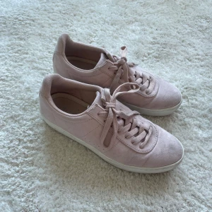 Rosa sneakers med snörning - Snygga rosa sneakers i mocka med klassisk snörning. Perfekta för en avslappnad stil. De har en vit sula som ger en fräsch kontrast till den mjuka rosa färgen.