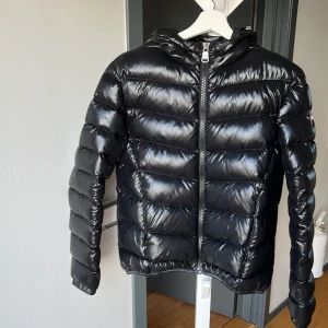 Svart dunjacka från Colmar - Snygg svart dunjacka från Colmar med glansig finish och dragkedja framtill. Storlek 44 i barnstorlek och sitter som en S. Den är oanvänd och köptes för ca 4000