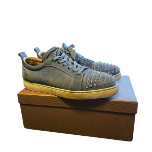 Christian Louboutin skor ljus blå - Snygga blå sneakers från Christian Louboutin med spikar i en ovanlig färg. Skorna har en klassisk snörning och en vit sula som ger en stilren kontrast. Perfekta för att ge din outfit en edgy touch. Skorna är i bra skick och har knappt använts. Skorna är bara lite smutsiga men går lätt att tvätta bort. Box och allt tillbehör ingår