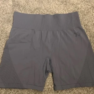 Grå träningsshorts - Snygga grå träningsshorts med hög midja och ribbade detaljer på sidorna. Perfekta för gymmet eller löprundan. De har en tight passform som ger bra stöd under träningen.