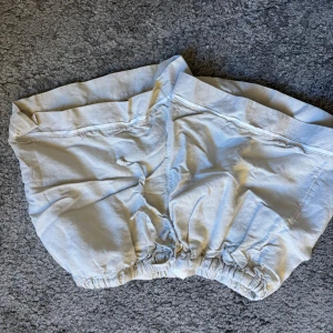 Vita shorts med resår - Säljer ett par vita shorts med resår i midjan. Perfekta för varma sommardagar. De är enkla och bekväma, gjorda i ett lätt material.