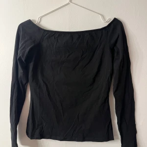Svart offshoulder topp - Snygg svart offshoulder topp med långa ärmar. Perfekt för en stilren look. Passar bra till både jeans och kjol.