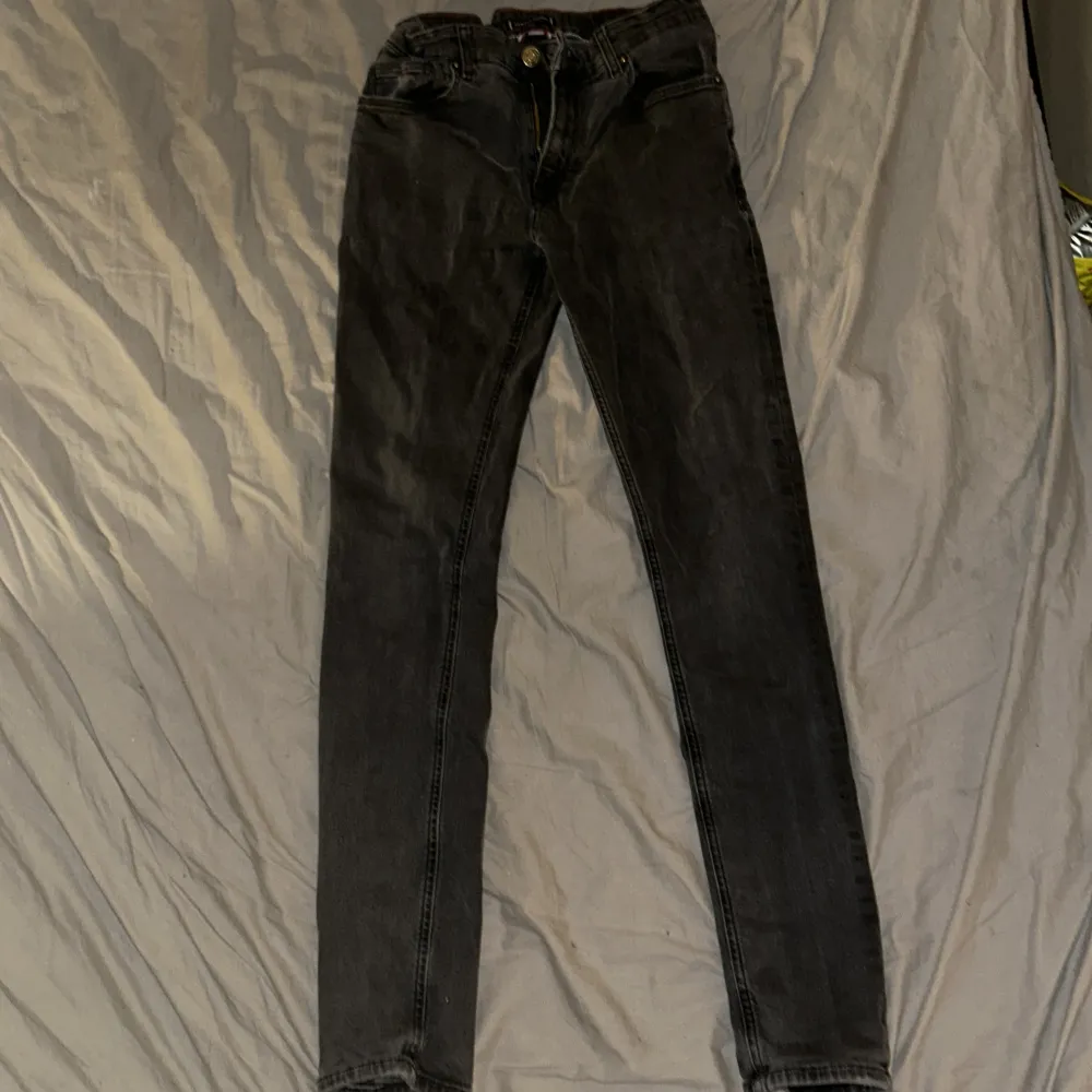 Snygga svarta jeans från Tommy Hilfiger med klassisk femficksdesign. De har en dragkedja och knapp framtill samt märkets logotyp på baksidan. Perfekta för en stilren look.. Farkut & Housut.