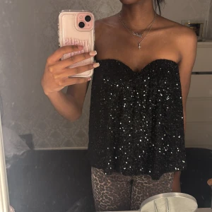 Svart paljett tubtopp - Snygg svart tubtopp täckt med glittrande paljetter. Perfekt för en kväll ute eller fest. Toppen är axelbandslös och har en lös passform som ger en bekväm känsla. Använd en gång. Lägg gärna prisförslag 