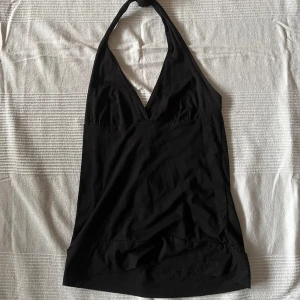 Svart halterneck topp från H&M - Snygg svart halterneck topp från H&M med djup v-ringning. Perfekt för en stilren look. Tillverkad i ett mjukt och bekvämt material. Storlek M men skulle säga att den passar bäst på en liten L